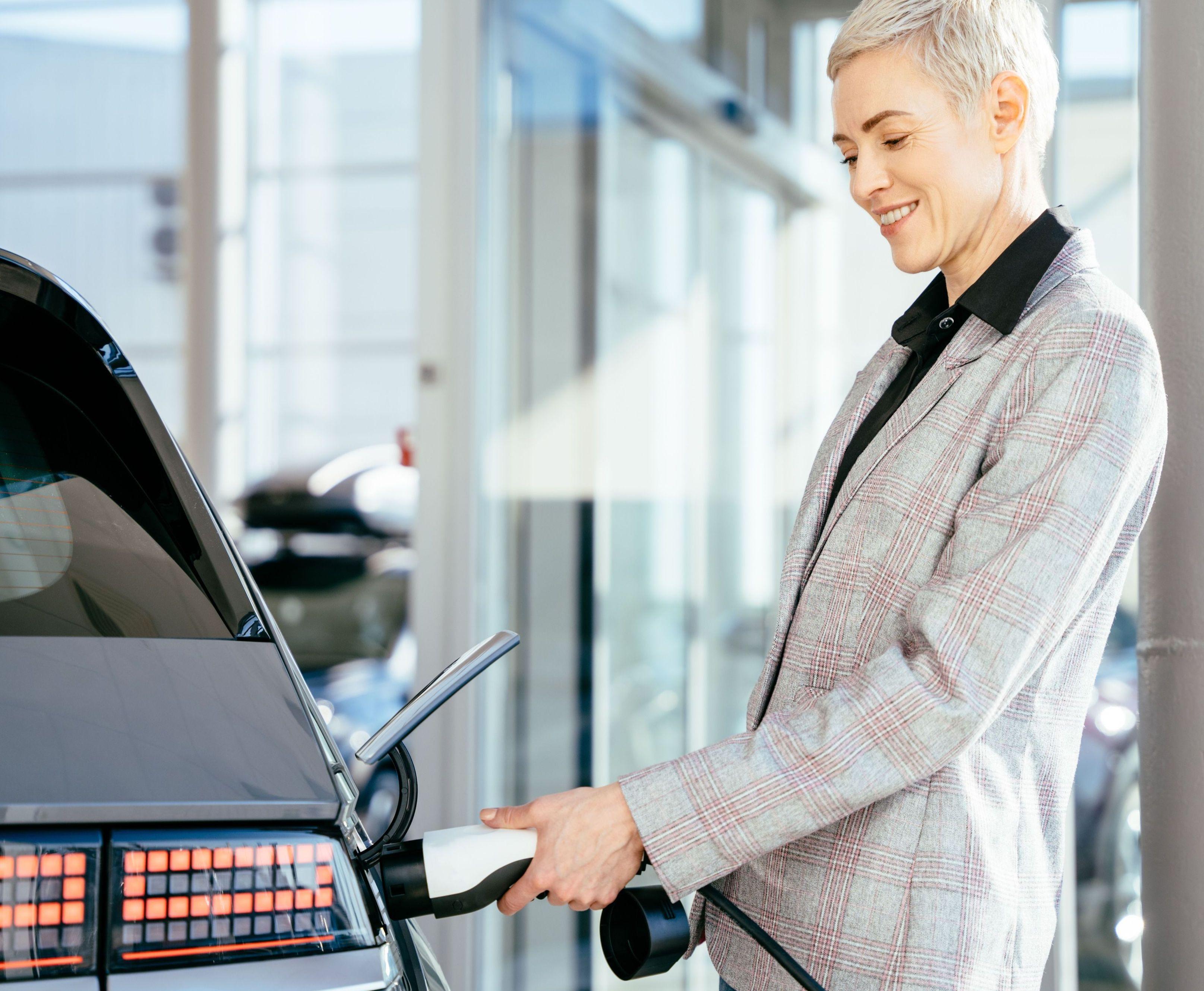 Frau steckt E-Auto an